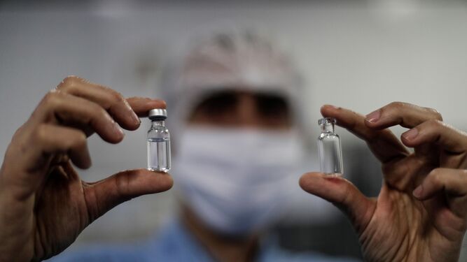 Un sanitario muestra dos frascos de vacunas.