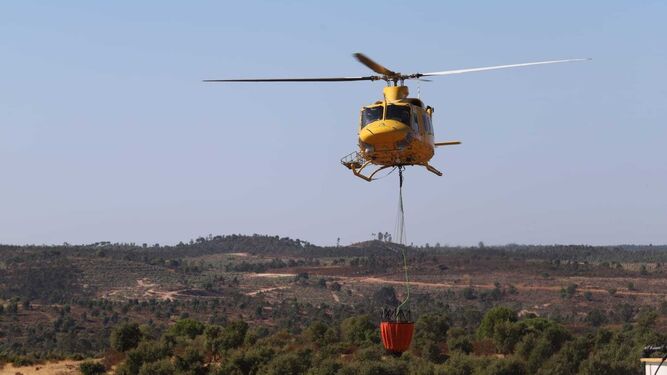Un helicóptero carga agua para las labores de extinción.