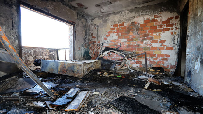Estado en el que quedó el salón de la vivienda afectada tras el incendio, punto de origen del fuego.