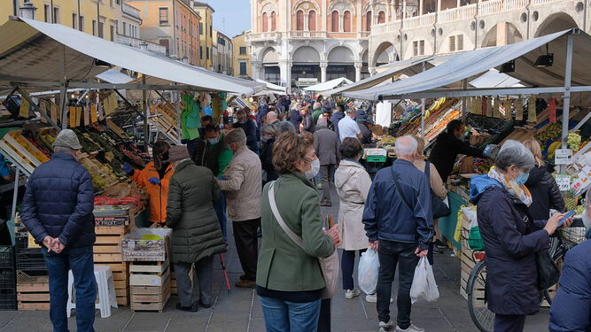 Personas con mascarilla compran en un mercado en una plaza de la ciudad italiana de Padua.
