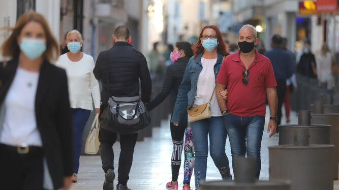 Los onubenses pasean por una calle del centro de la capital onubense durante la actual pandemia de coronavirus.