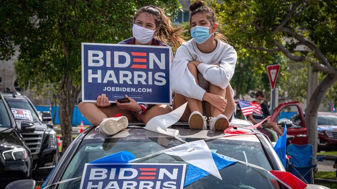 Dos jóvenes  sostienen una pancarta de apoyo a la fórmula "Biden Harris".