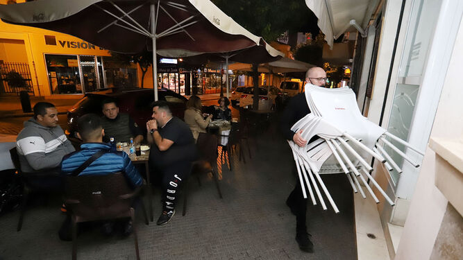 Un camarero recoge las sillas en un bar de Huelva