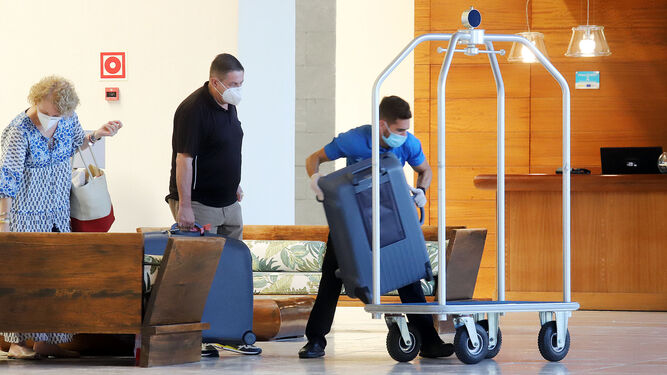 Un trabajador de un hotel onubense ayuda a mover las maletas de unos turistas.