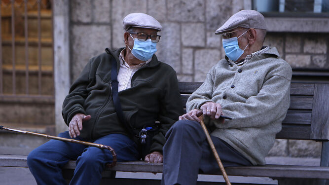 Dos ancianos charlan ataviados con mascarillas