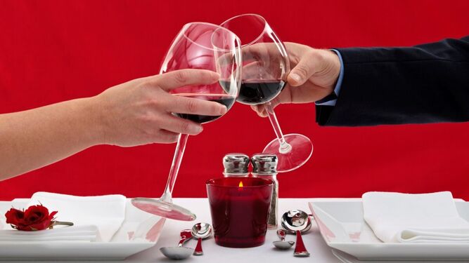 Una pareja brinda con vino antes de degustar un menú especial por el Día de San Valentín.