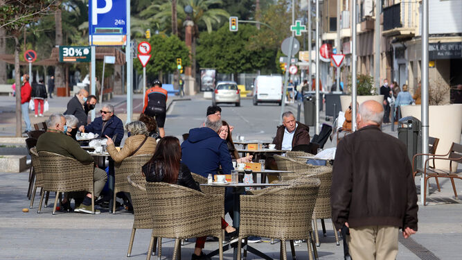 Varias personas disfrutan de la mañana en una terraza junto al Mercado del Carmen de Huelva.