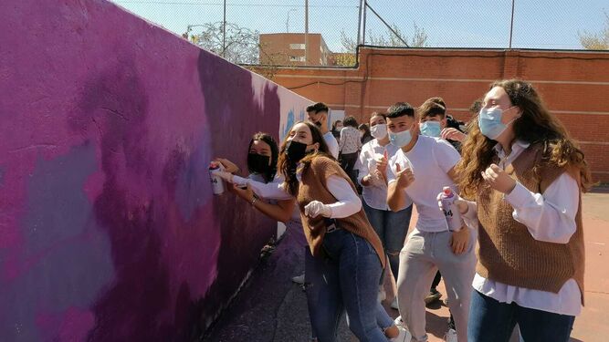 Alumnos aplican con entusiasmo spray con simbólicos tonos violeta.