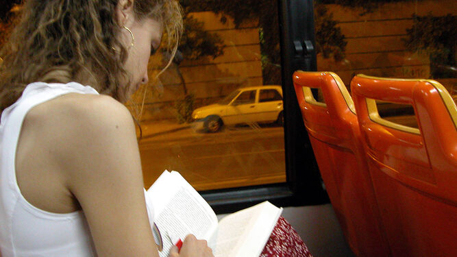 Una joven lee un libro en un autobús urbano.