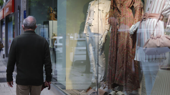 Un hombre camina junto al escaparate de una tienda de moda femenina.