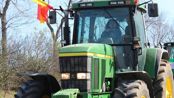 Agricultora conduciendo un tractor por su explotación.