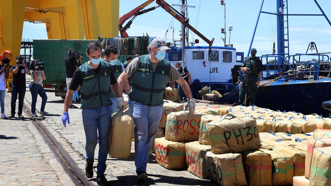 Varios agentes de la Guardia Civil portan fardos de droga pertenecientes a la incutación obtenida en la operación conjunta con la Policía Judiciaria de Portugal.