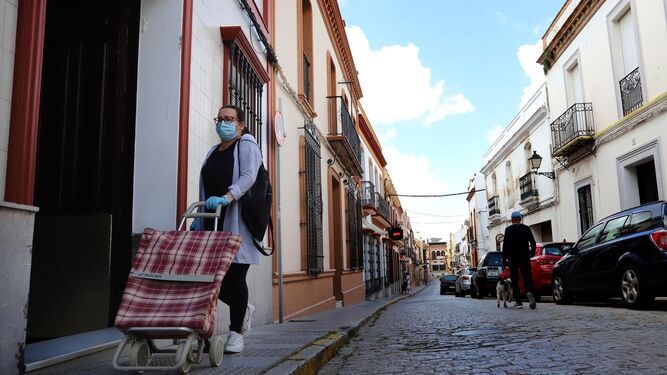 Una mujer camina con un carro de la compra por la localidad de Bonares.