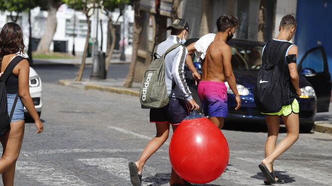 Un grupo de jóvenes pasea por Huelva con sus mascarillas.