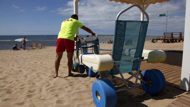 Un socorrista ordena el material para personas con discapacidad en una playa de Isla Cristina