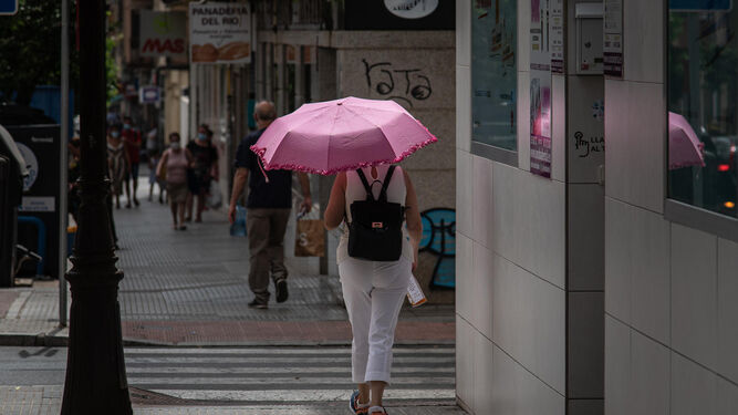 Un joven se protege del sol con un paraguas.