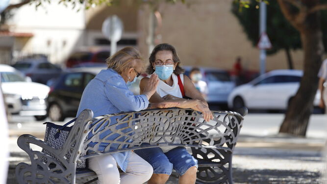 Dos mujeres conversan en un banco con sus mascarillas de protección contra la Covid-19.