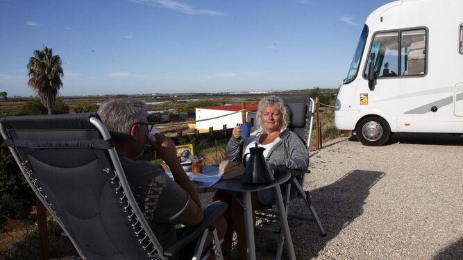 Dos alemanes desayunan en Camper Park Playas de Luz, con las marismas al fondo