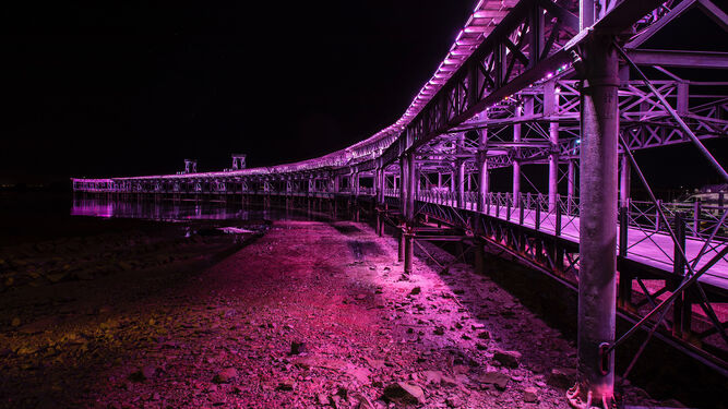 Muelle de la Río Tinto iluminado de rosa.