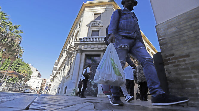 Un onubense cruza por las inmediaciones de la Plaza de las Monjas con unas bolsas de la compra.