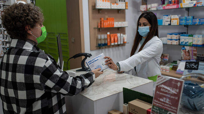 Una cliente compra un test de antígenos en una farmacia de Huelva.