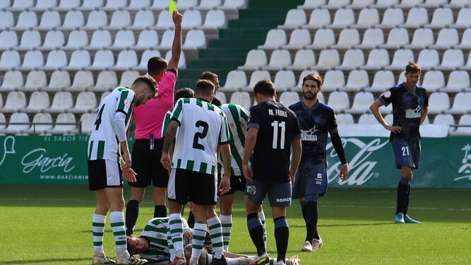 El colegiado muestra una tarjeta amarilla a un jugador del Recreativo de Huelva en su visita al Córdoba B.