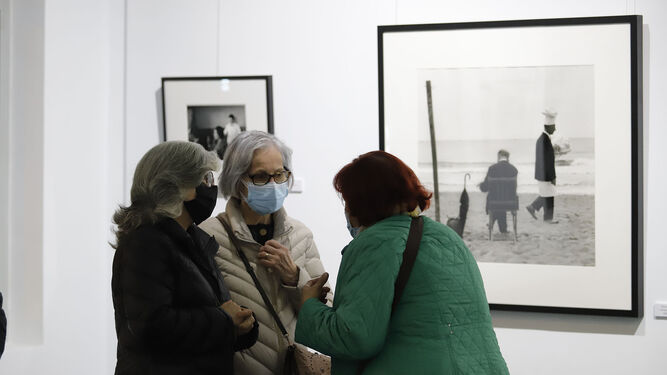Un grupo de mujeres charlando ante una de las fotos de la exposición.