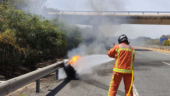 Momento en que un bombero lucha contra las llamas que afectan a uno de los neumáticos