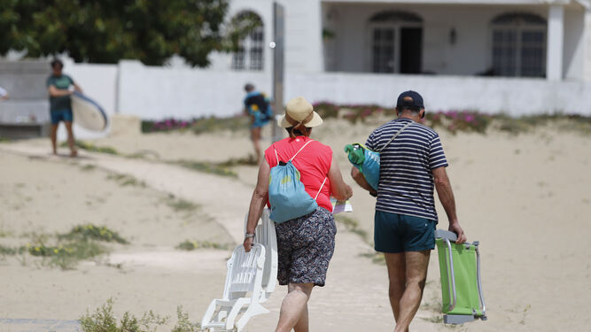 Dos personas abandonan la playa del Portil tras disfrutar de la jornada del domingo.