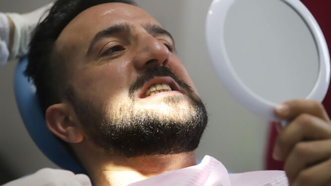Un paciente revisa su dentadura tras una intervención en la clínica solidaria de Gibraleón.