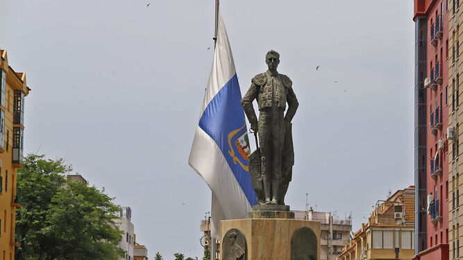 LItri en su monumento en su barrio de San Sebastián, con la bandera de HUelva a media asta.