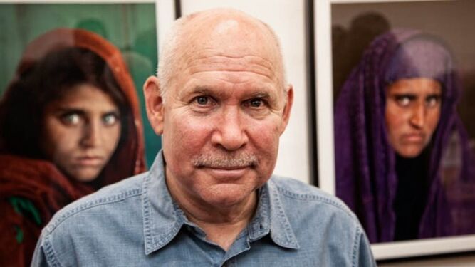 Steve McCurry junto a su famosa foto de la chica afgana.