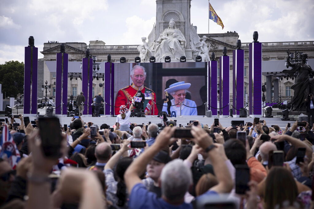 Los londinenses siguen en una pantalla el saludo de la reina y el pr&iacute;ncipe de Gales