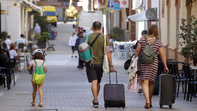 Una familia camina con maletas de viaje por el centro de Huelva en el día de ayer.