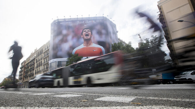 Una enorme lona con un triunfador Carlos Alcaraz en una avenida de Barcelona.