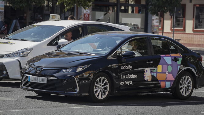 Un 'cabify' circula junto a un taxi en las calles de Sevilla