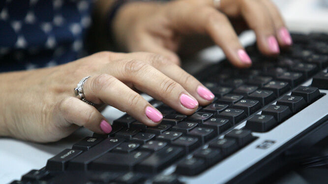 Una mujer teclea el ordenador en su trabajo.