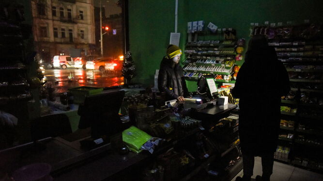 Una vendedora usa su teléfono móvil para tener luz en Kiev.
