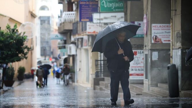 Un hombre pasea por el centro de Huelva bajo la lluvia en una imagen de archivo.