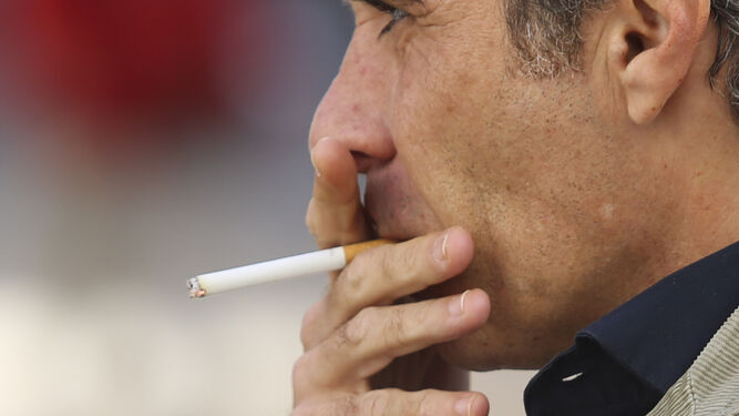 Un hombre fuma un cigarrillo.
