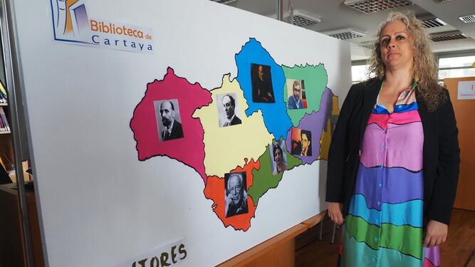 La filóloga Nuria Bayo junto a un mapa con autores andaluces en la biblioteca de Cartaya
