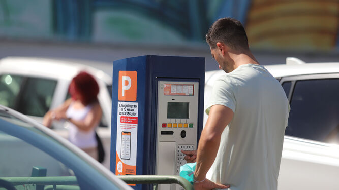 Un hombre realiza un pago en un parquímetro de Huelva.