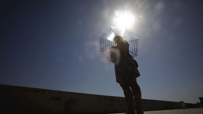 Una mujer se protege del tiempo con un paraguas en Huelva
