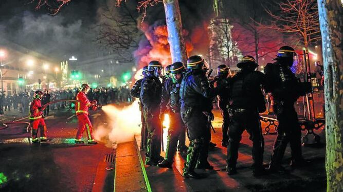 Bomberos apagan un fuego durante las protestas en París contra la reforma de las pensiones.