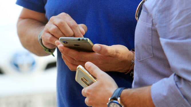 Imagen de archivo de dos personas con su teléfono móvil.