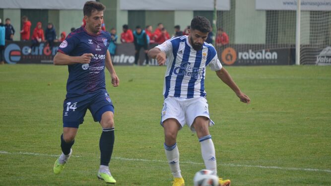 Manu Galán controla el balón bajo la presión de Fer Llorente.