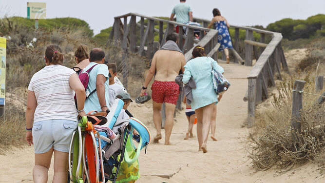Varias personas en la pasarela de madera de una de las playas de Huelva.