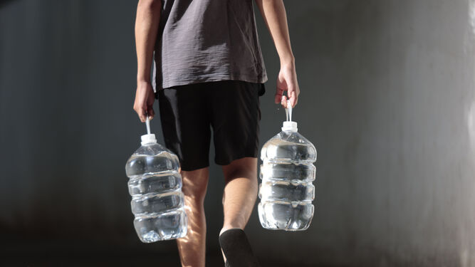 Un ciudadano porta botellas de agua ante la escasez de agua corriente por las noches