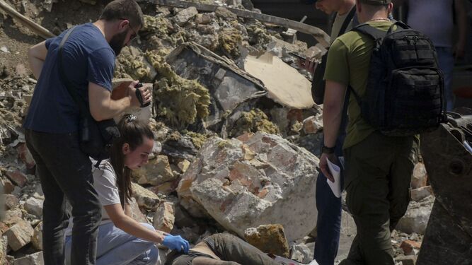 Efectivos de emergencias permanecen junto al cuerpo de uno de los fallecidos en el ataque a Odesa.
