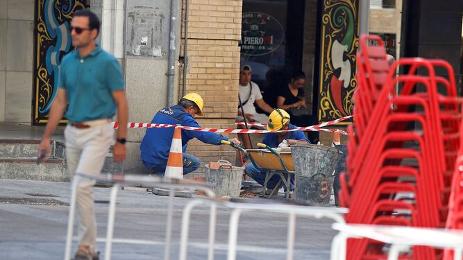 Dos operarios en una obra en el centro de Huelva, en pleno mes de julio.